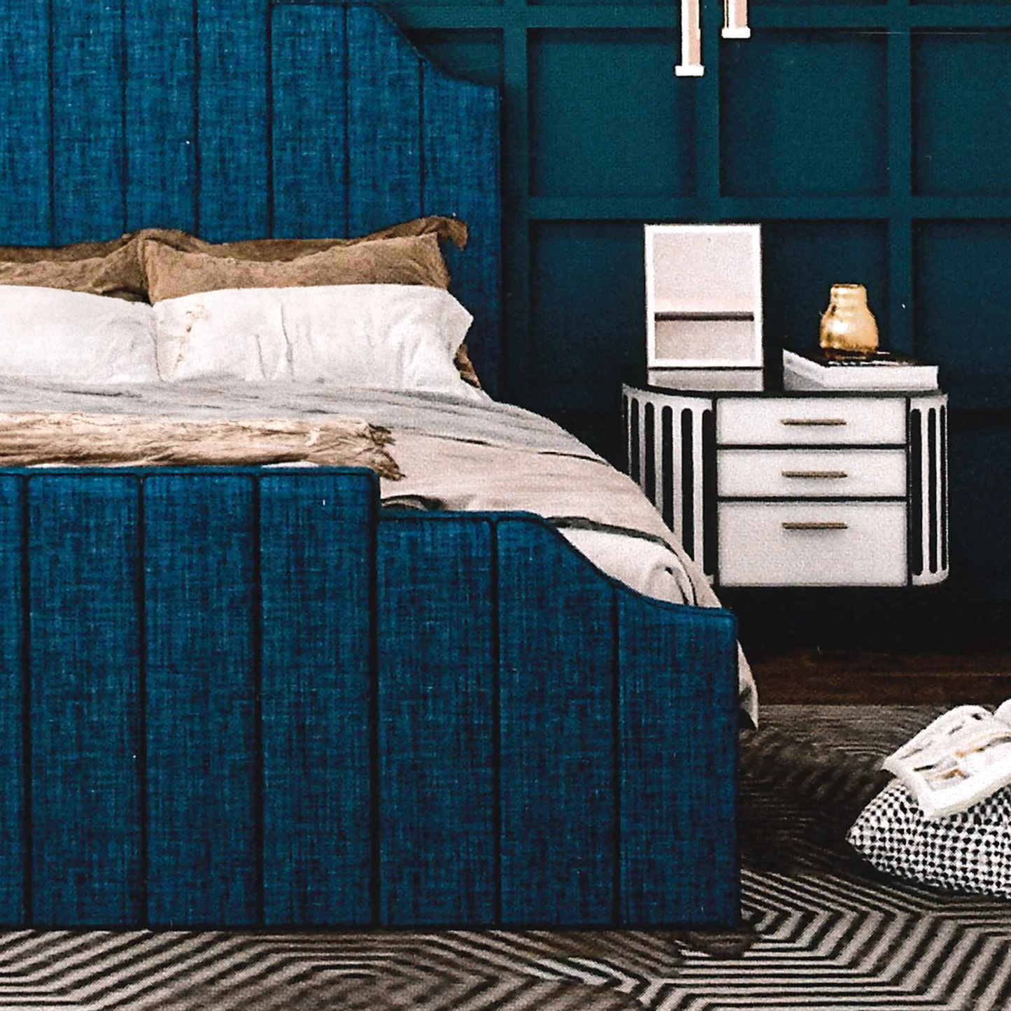 Modern bedroom with a blue upholstered bed footboard and white nightstands.