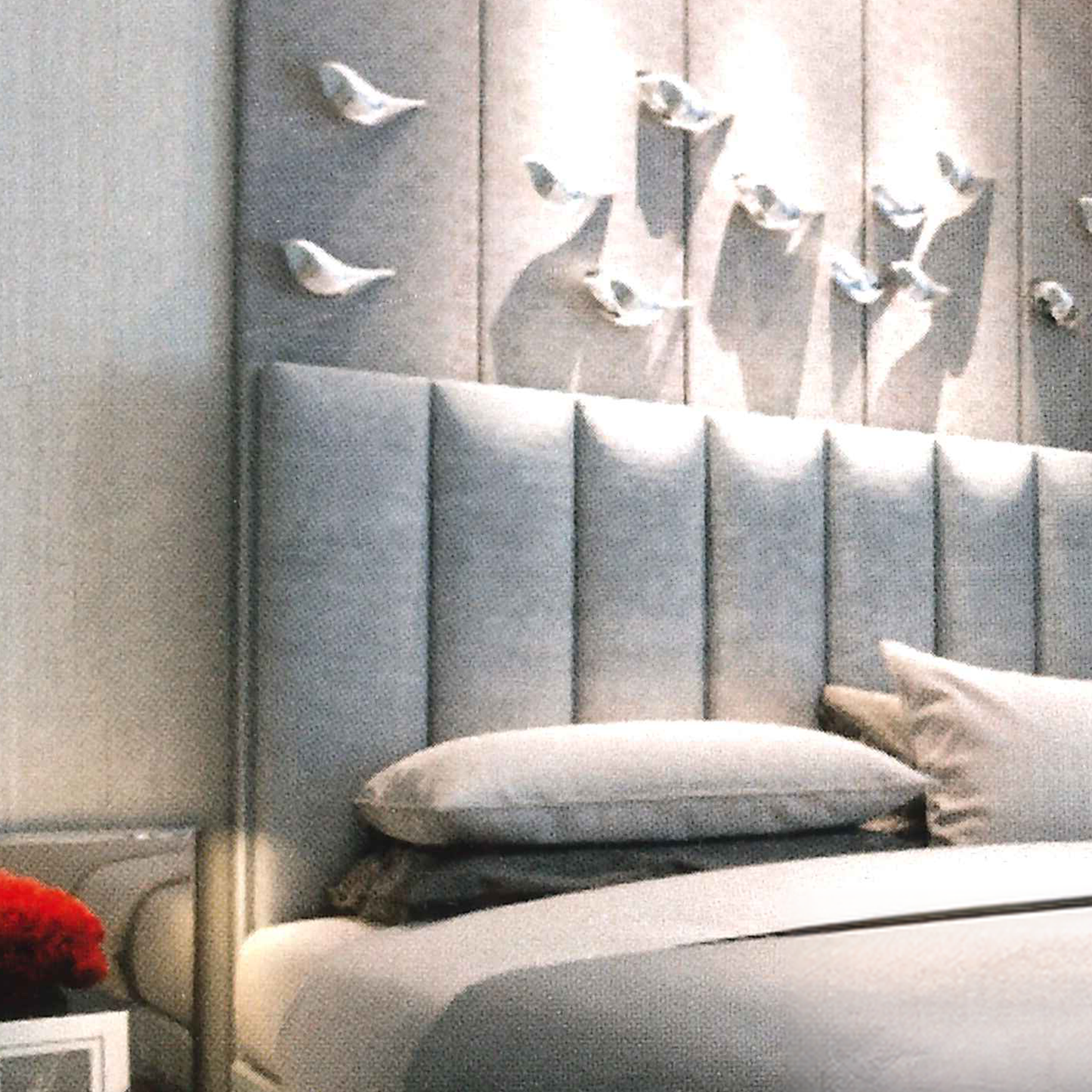 Gray upholstered headboard with decorative pillows against a wall with abstract art.