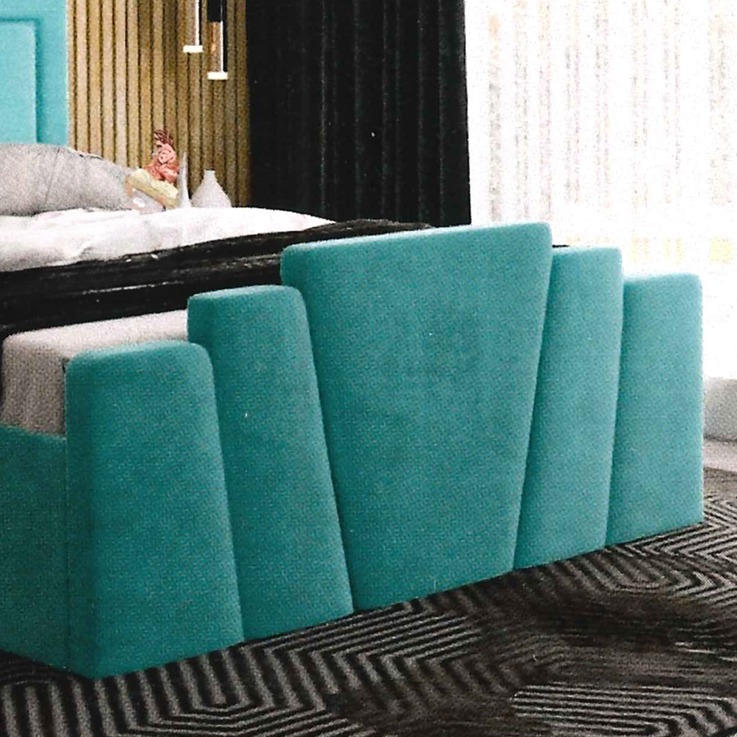 Teal upholstered footboard against a bedroom wall with a bed and window in the background.