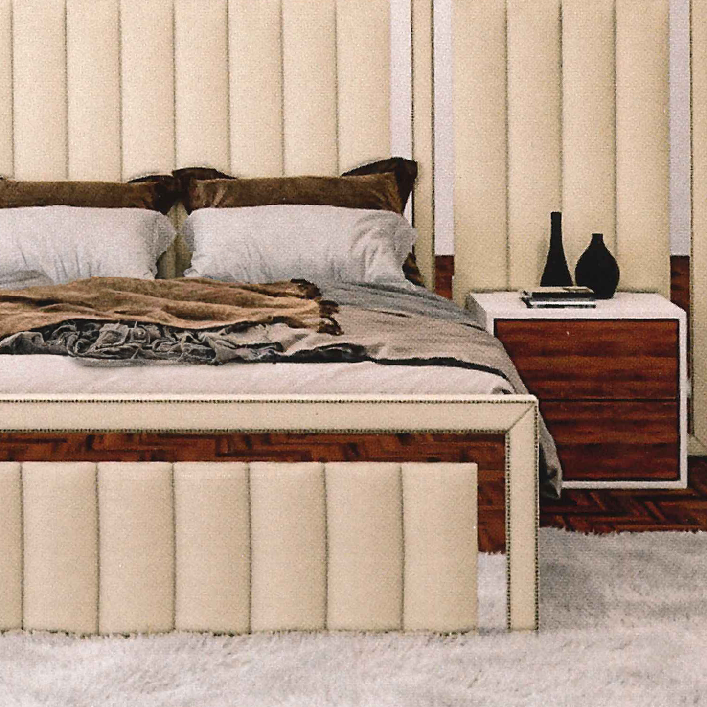 Neatly made bed with decorative pillows and a wooden nightstand in a bedroom setting.