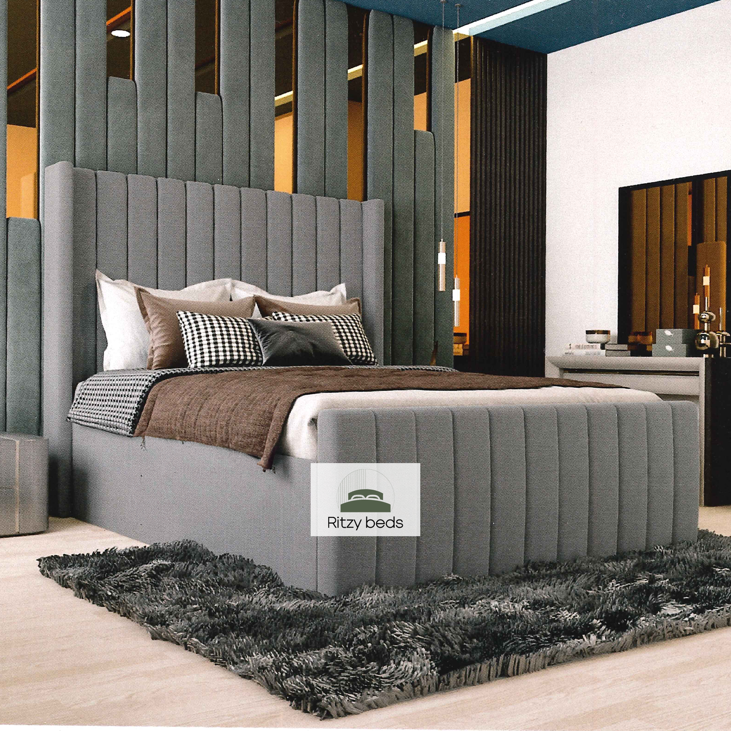 Gray upholstered bed with decorative pillows in a modern bedroom setting, featuring the 'Ritzy Beds' brand.