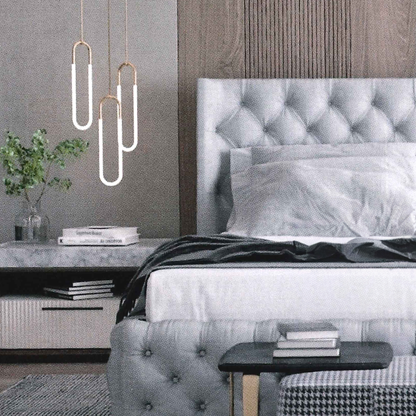 Modern bedroom with gray buttoned tufted bed and decorative pendant lights.