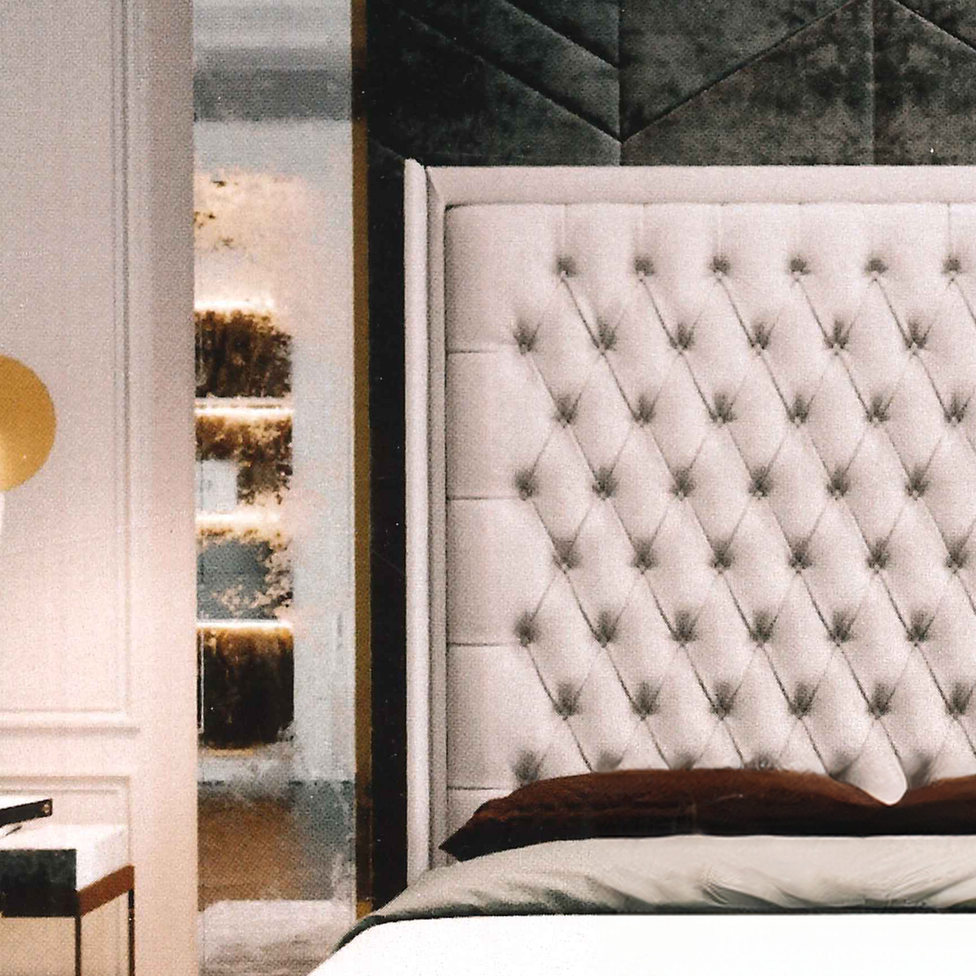 Tufted headboard in a bedroom setting with decorative wall lighting.