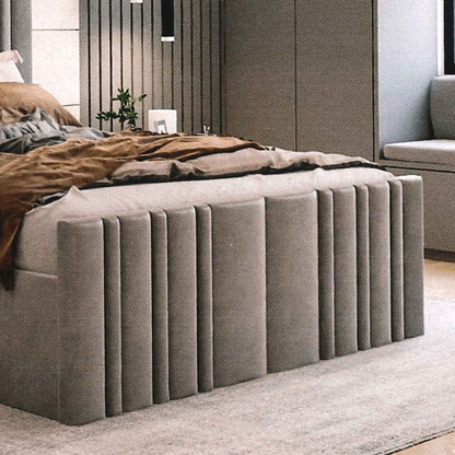 Gray upholstered lined footboard matching in a bedroom setting with bedding and decor.