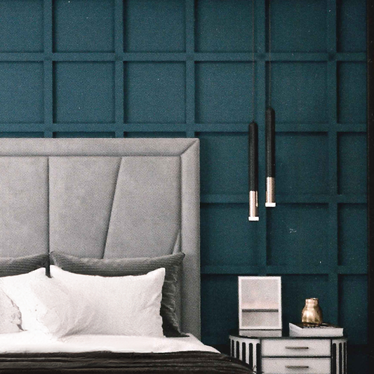 Gray geometric british upholstered headboard against a teal paneled wall with a nightstand.