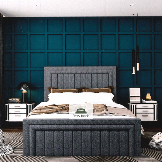 Gray upholstered urban metropolitan tufted bed with white bedding against a blue paneled wall in a modern bedroom.