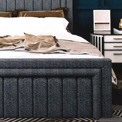 Gray upholstered bed, matching footboard with white bedding and brown pillows in a bedroom setting.