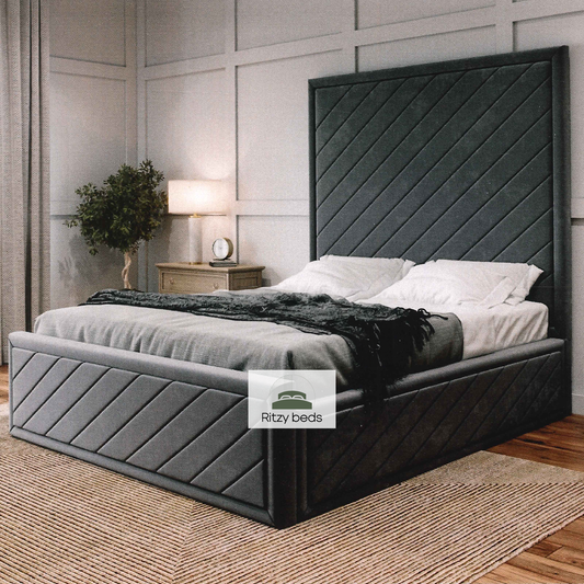 Gray upholstered bed with a modern angular handmade headboard in a bedroom setting, featuring the 'Ritzy Beds' brand.