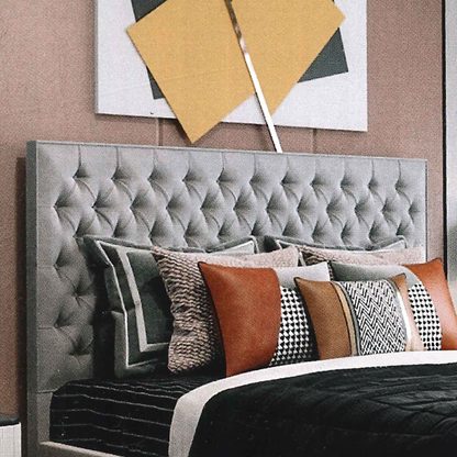 Gray luxury tufted headboard with decorative pillows against a wall with abstract art.