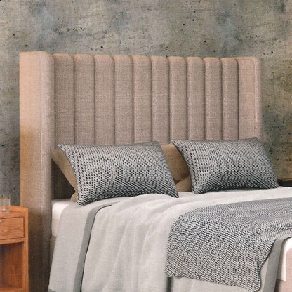 Bed with textured headboard and gray bedding against a concrete wall.