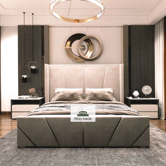 Gray upholstered bed with angular geometric lines in a modern bedroom with 'Ritzy Beds' branding.