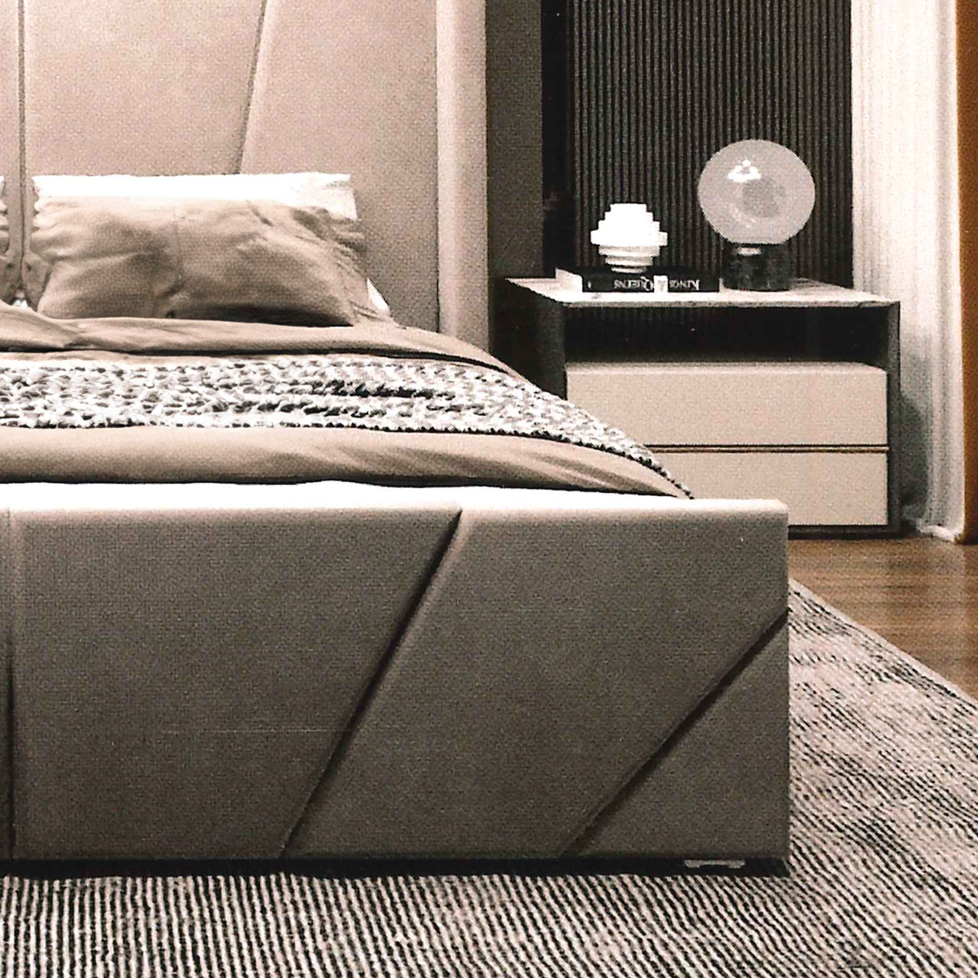 Modern bedroom with a gray upholstered luxury bed footboard and nightstand.
