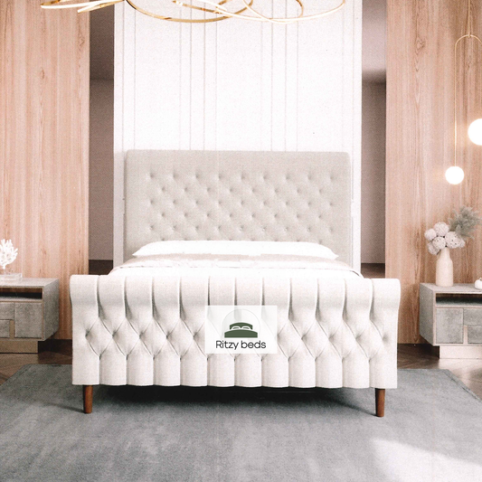 White tufted scroll luxury bed with 'Ritzy beds' logo in a bedroom setting