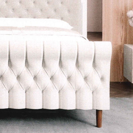 Tufted scroll handmade bespoke bed skirt on a bed with a wooden leg in a bedroom setting