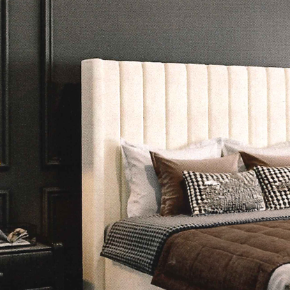 Beige upholstered headboard with decorative pillows and blankets in a bedroom setting.