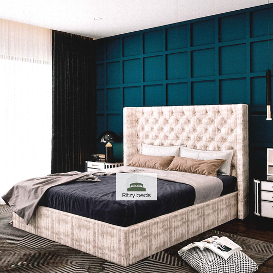Bedroom with a tufted winged bed and decorative wall, featuring the Ritzy Beds logo.