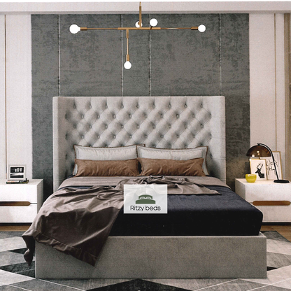 Gray upholstered bed with tufted headboard in a modern bedroom setting, featuring the 'Ritzy Beds' brand.