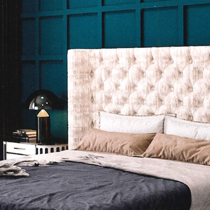 Bedroom with a tufted headboard and decorative pillows against a teal wall.